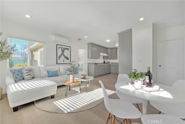 living room with a wall mounted AC and light hardwood / wood-style flooring