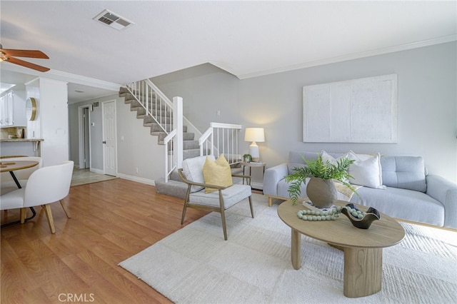 living room with light hardwood / wood-style floors, ornamental molding, and ceiling fan