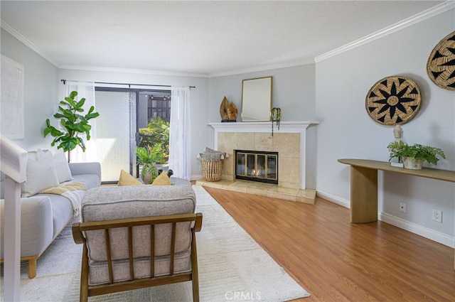 living room with hardwood / wood-style flooring, a tile fireplace, and crown molding