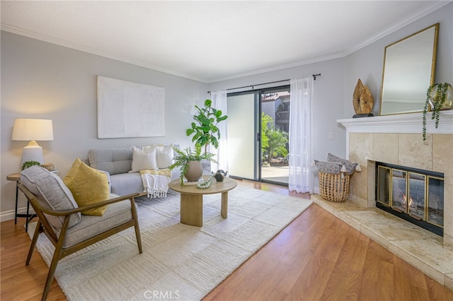 living room featuring a tile fireplace, crown molding, and light hardwood / wood-style flooring