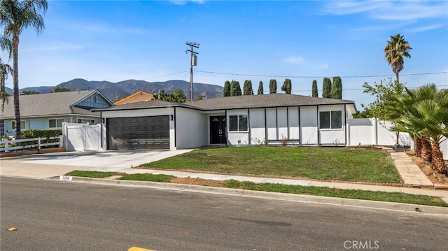 ranch-style home with a front lawn, a mountain view, and a garage