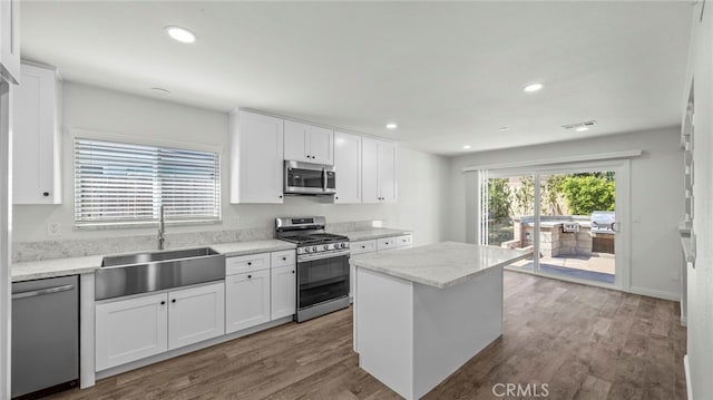 kitchen with appliances with stainless steel finishes, a center island, white cabinetry, and sink