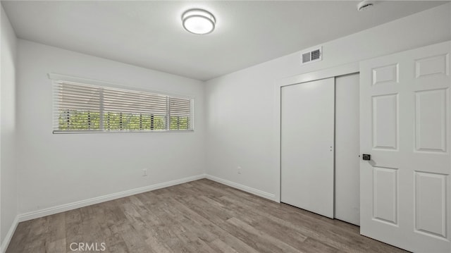 unfurnished bedroom featuring light hardwood / wood-style flooring and a closet