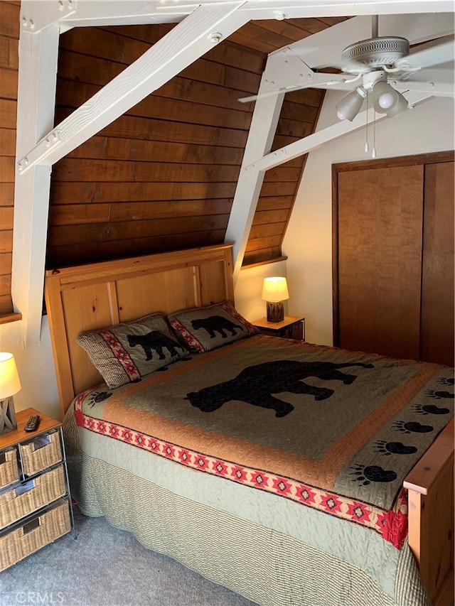 bedroom with ceiling fan, wood walls, and carpet