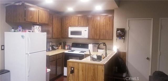 kitchen featuring kitchen peninsula, dark hardwood / wood-style flooring, and white appliances