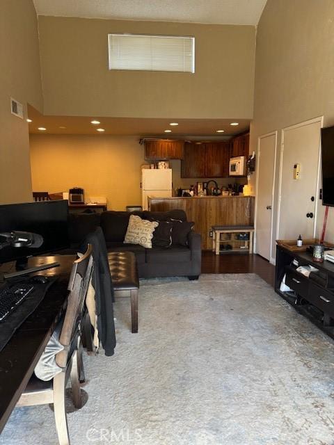 carpeted living room featuring a towering ceiling