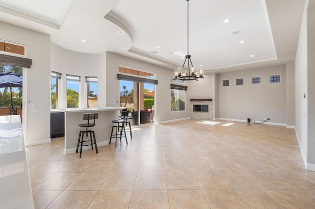 kitchen with decorative light fixtures, a breakfast bar area, light tile patterned floors, a raised ceiling, and an inviting chandelier