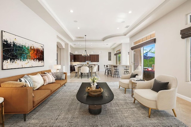 living room featuring light tile patterned floors, a raised ceiling, and a chandelier