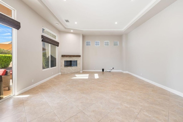 unfurnished living room with light tile patterned flooring, a premium fireplace, and a raised ceiling