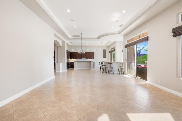 unfurnished living room featuring ornamental molding, light tile patterned floors, and a tray ceiling