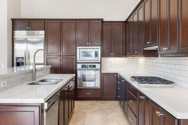 kitchen featuring sink, tasteful backsplash, built in appliances, light tile patterned floors, and light stone countertops