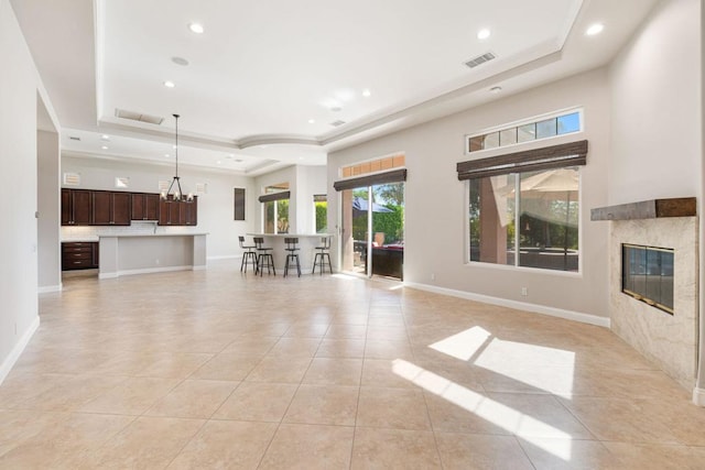 unfurnished living room featuring a premium fireplace, a raised ceiling, and light tile patterned floors