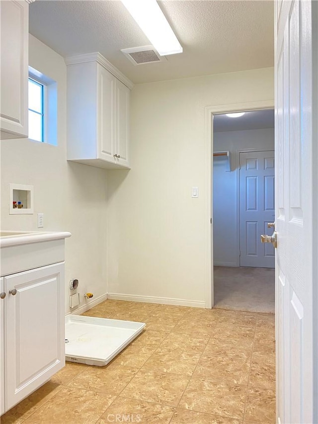 laundry room featuring washer hookup, cabinets, and a textured ceiling