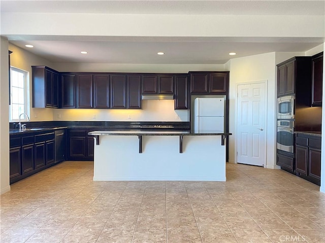 kitchen with sink, a breakfast bar, a kitchen island, and appliances with stainless steel finishes