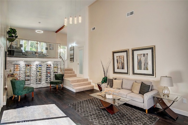 living room with a towering ceiling and dark hardwood / wood-style flooring