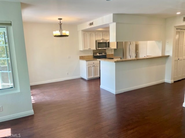 kitchen with kitchen peninsula, appliances with stainless steel finishes, dark hardwood / wood-style flooring, decorative light fixtures, and white cabinets