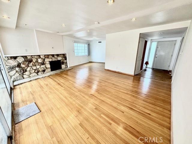 unfurnished living room featuring light hardwood / wood-style flooring and a stone fireplace