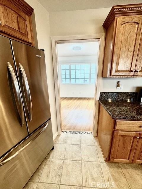 kitchen featuring stainless steel fridge, light wood-type flooring, and dark stone counters