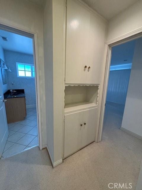 hallway featuring light colored carpet and sink