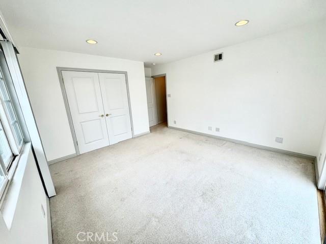 unfurnished bedroom with light colored carpet and a closet