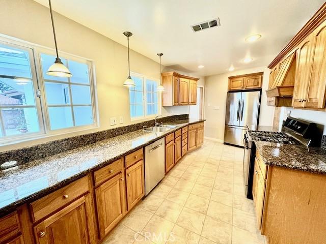 kitchen with sink, dark stone countertops, hanging light fixtures, and appliances with stainless steel finishes