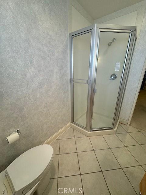 bathroom with tile patterned flooring, an enclosed shower, and toilet