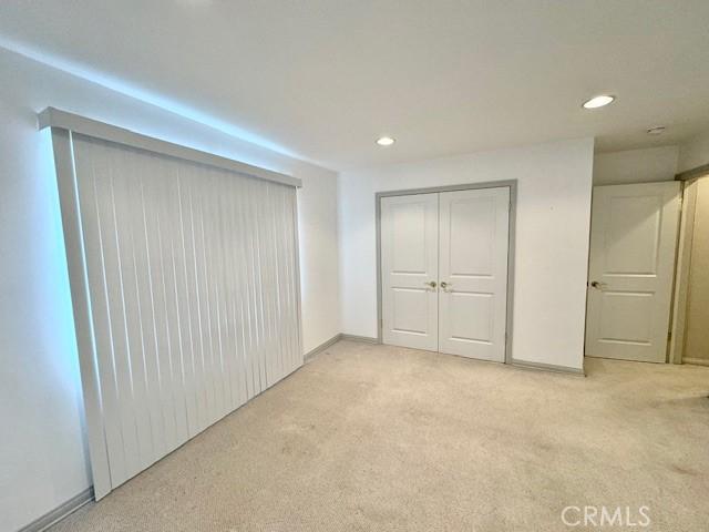 unfurnished bedroom with light colored carpet and a closet