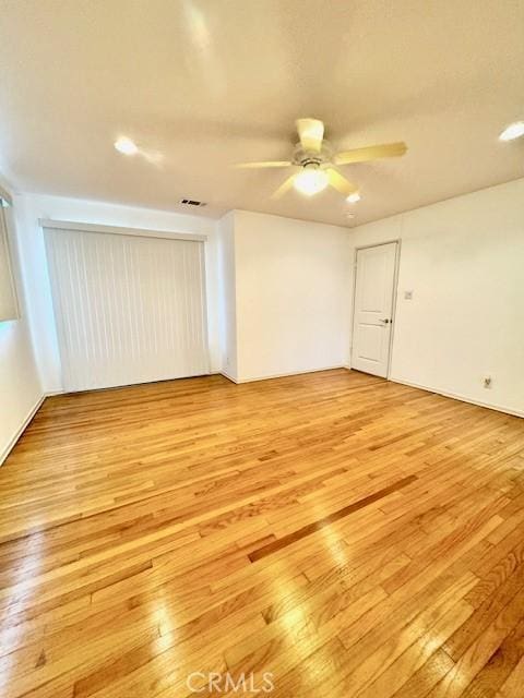 empty room with light wood-type flooring and ceiling fan