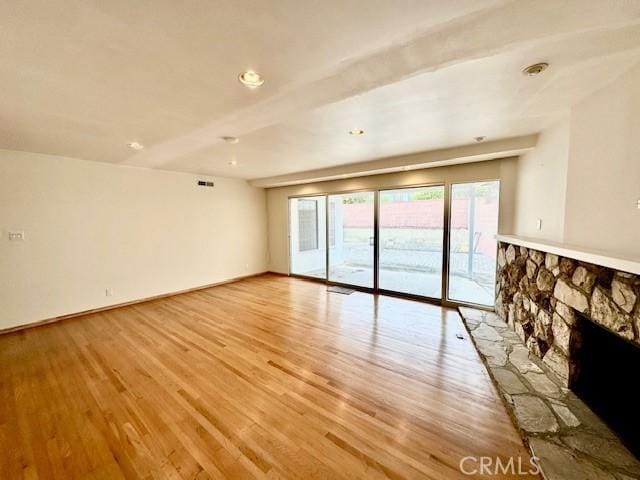 unfurnished room featuring a fireplace and light hardwood / wood-style flooring