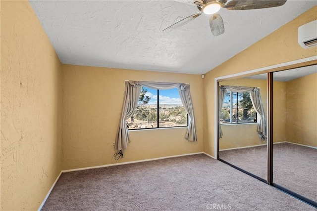 unfurnished bedroom featuring lofted ceiling, carpet floors, a closet, a wall unit AC, and ceiling fan