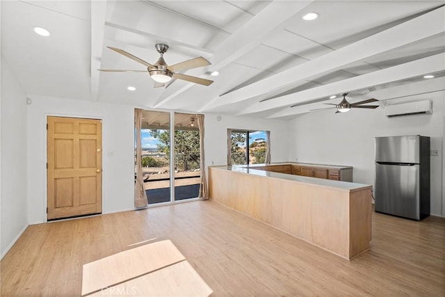 kitchen with a wall mounted AC, lofted ceiling with beams, stainless steel refrigerator, and light hardwood / wood-style floors