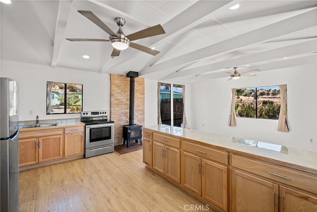 kitchen featuring stainless steel appliances, a wood stove, sink, light hardwood / wood-style flooring, and lofted ceiling with beams