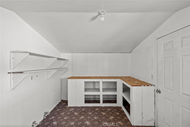 interior space featuring vaulted ceiling and dark colored carpet