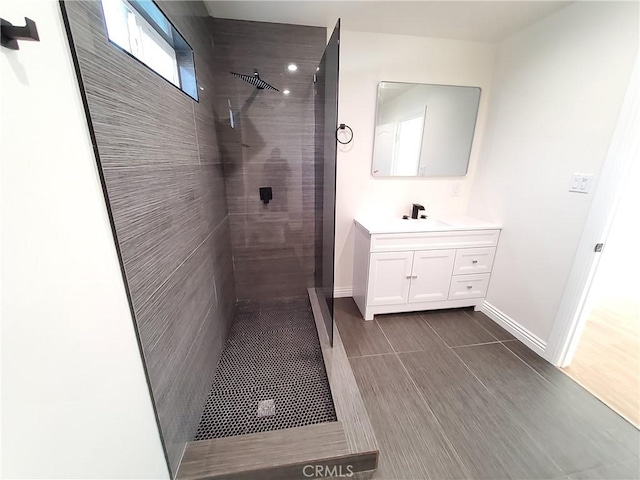 bathroom with tiled shower and vanity