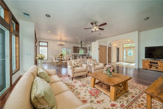 living room featuring ceiling fan with notable chandelier and light hardwood / wood-style flooring