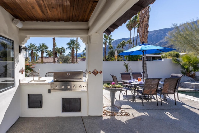 view of patio / terrace featuring area for grilling, a mountain view, sink, and a grill