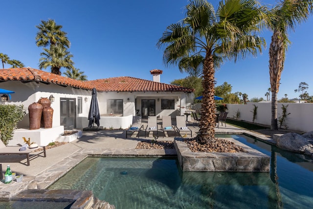 rear view of property with a fenced in pool and a patio