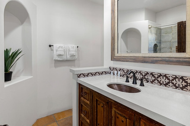 bathroom with tile patterned floors, tiled shower, and vanity