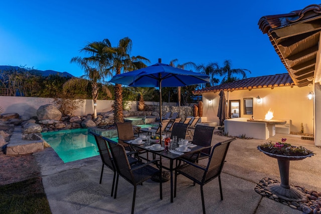 patio terrace at dusk with a mountain view and a fenced in pool