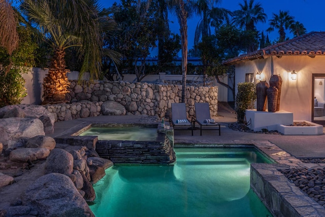 pool at twilight featuring an in ground hot tub and a patio