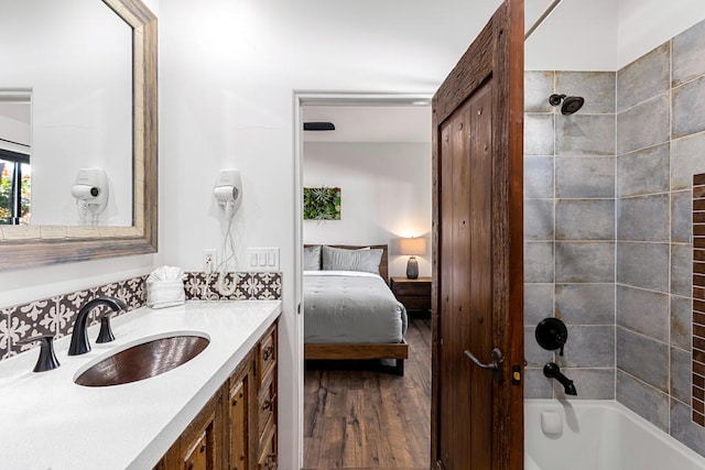 bathroom with wood-type flooring, tiled shower / bath, and vanity