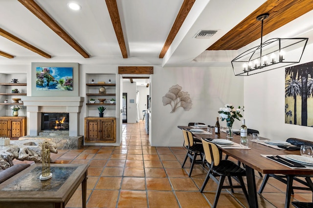 tiled dining area with built in features, beam ceiling, and a notable chandelier