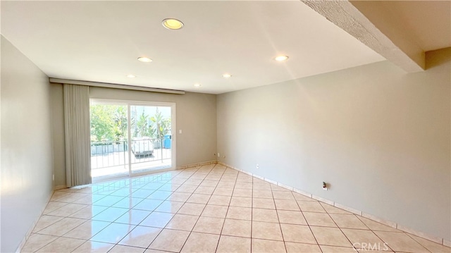 spare room featuring beamed ceiling and light tile patterned floors