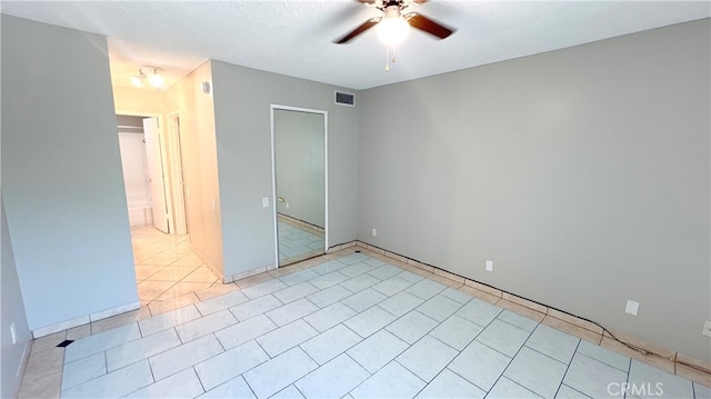 unfurnished bedroom featuring light tile patterned flooring, a textured ceiling, and ceiling fan