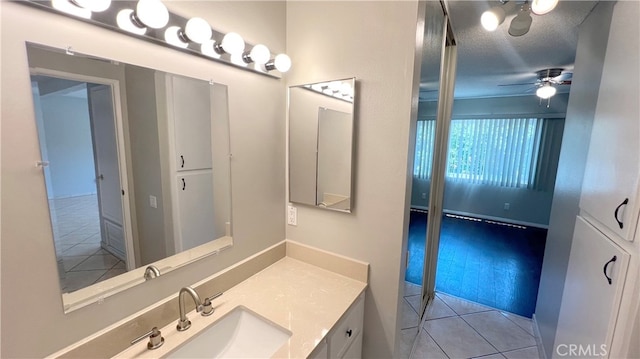 bathroom with tile patterned flooring, a textured ceiling, vanity, and ceiling fan