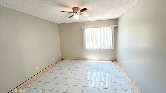 tiled empty room with ceiling fan and a textured ceiling