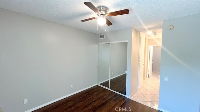 unfurnished bedroom featuring light hardwood / wood-style flooring, ceiling fan, a closet, and a textured ceiling