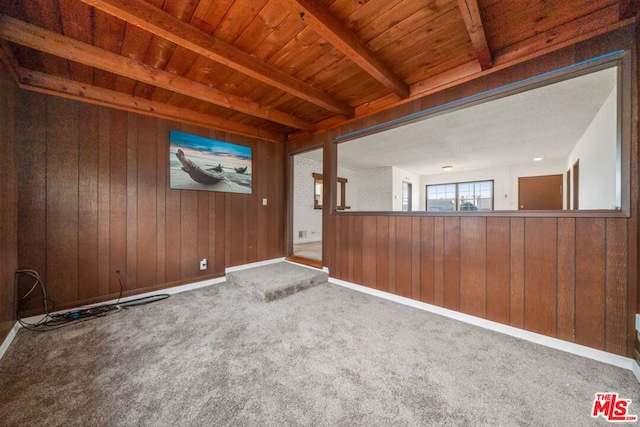 empty room featuring beamed ceiling, carpet flooring, wooden ceiling, and wood walls