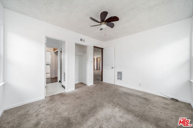 unfurnished bedroom featuring a closet, ceiling fan, light colored carpet, and a textured ceiling