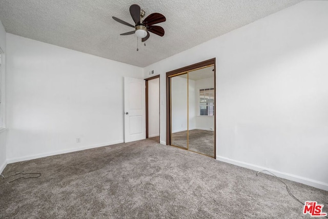 unfurnished bedroom with a textured ceiling, carpet floors, a closet, and ceiling fan